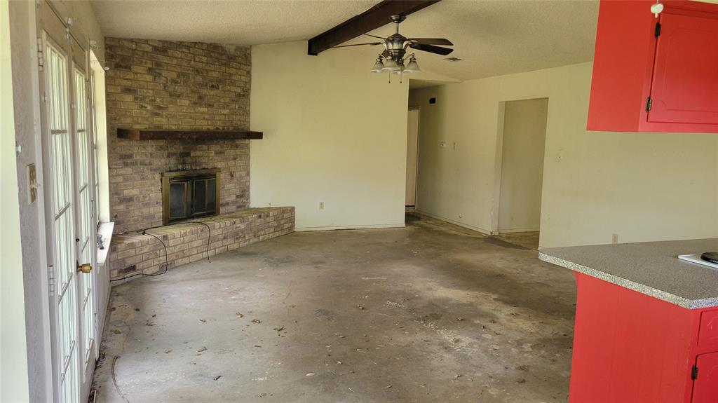 902 South Old Temple Road Hewitt, TX 76643 - Photo 3 of 32 Exposed brick fireplace with a wood mantle, French doors, ceiling fan, and L-shaped countertop