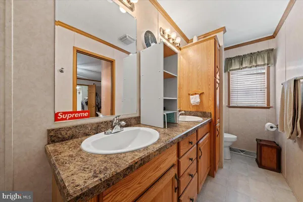 a bathroom with a granite countertop sink a mirror and a toilet