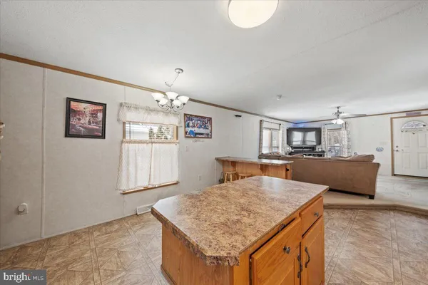 a living room with stainless steel appliances kitchen island granite countertop furniture and rug