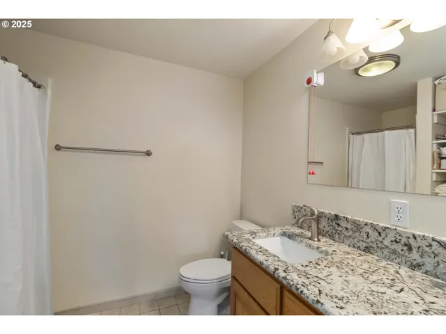 a bathroom with a granite countertop sink toilet and a mirror