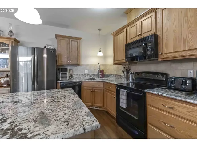 a kitchen with stainless steel appliances granite countertop a refrigerator stove top oven and sink