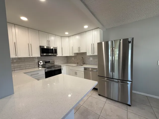 a kitchen with granite countertop a refrigerator sink and microwave