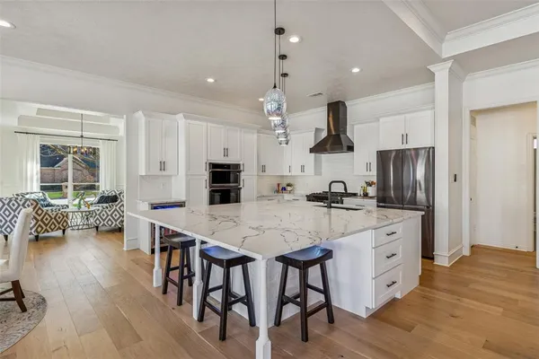 a kitchen with stainless steel appliances a dining table chairs stove and refrigerator