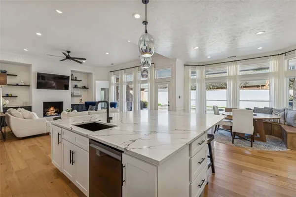 a kitchen with stainless steel appliances granite countertop a stove oven a refrigerator a kitchen island a dining table and chairs with wooden floor