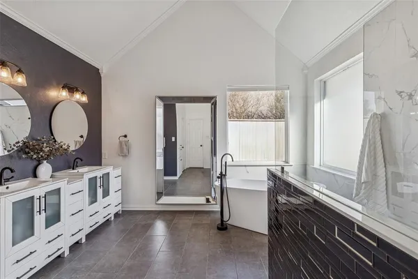 a en suite bathroom with a double vanity sink a mirror and a bathtub