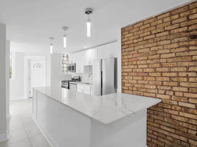 a large kitchen with stainless steel appliances a large counter top a stove and a refrigerator