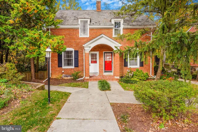 a view of a brick house with a yard and large tree