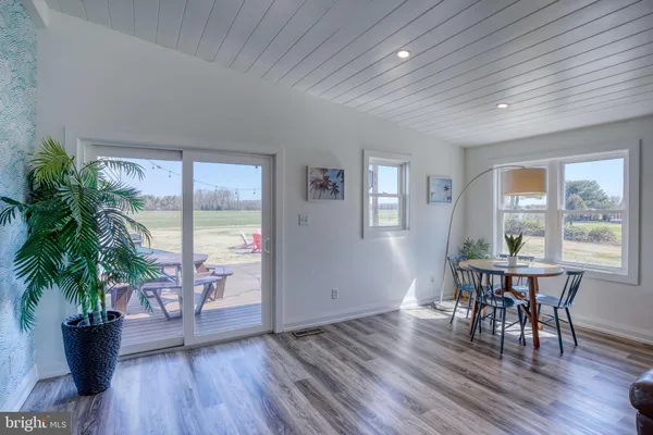 a kitchen with granite countertop a stove a sink a dining table and chairs with wooden floor