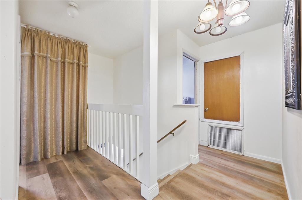 3027 Queens Gate Road Orlando, FL 32818 - Photo 31 of 34 a view of a hallway to a room with wooden floor windows and entryway