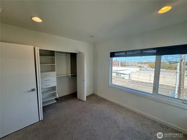 a view of an empty room with a window and bathroom