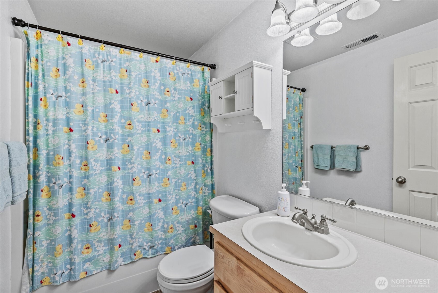 2410 North Heron Drive Ridgefield, WA 98642 - Photo 29 of 40 a bathroom with a sink a toilet a mirror and shower curtain