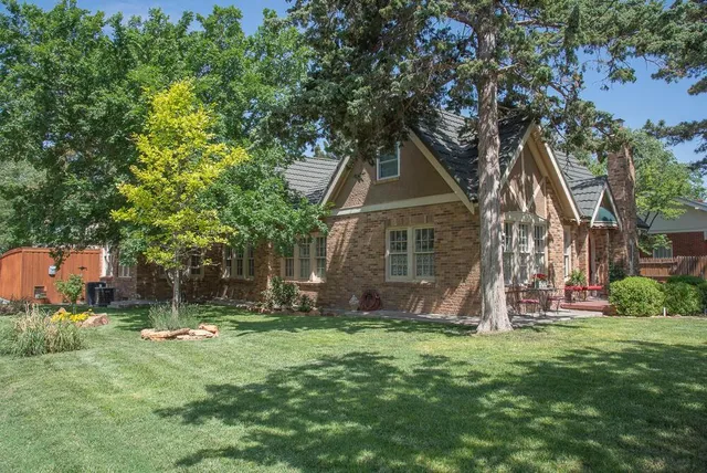 a view of a house with a wooden fence and a large tree