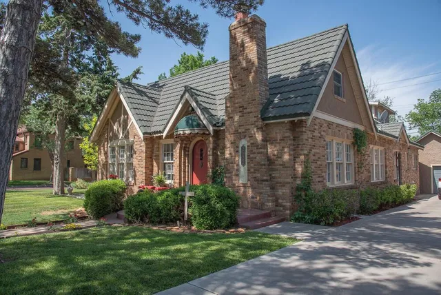 a view of a big house with a big yard potted plants and large tree