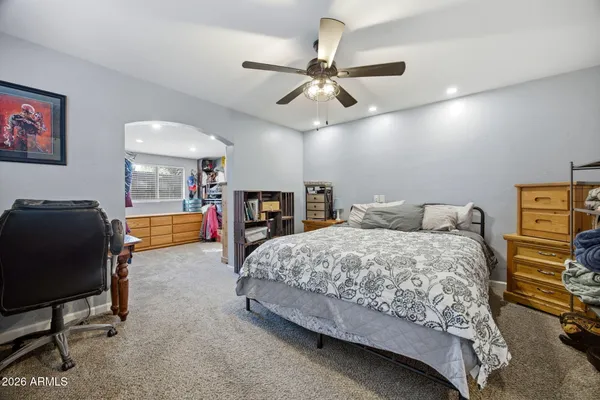 a spacious bedroom with a bed a dresser and a chandelier