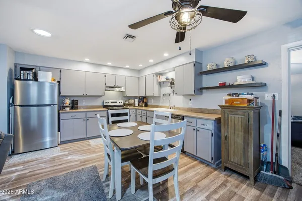 a kitchen with stainless steel appliances granite countertop a refrigerator a sink dishwasher a stove and a refrigerator with wooden floor