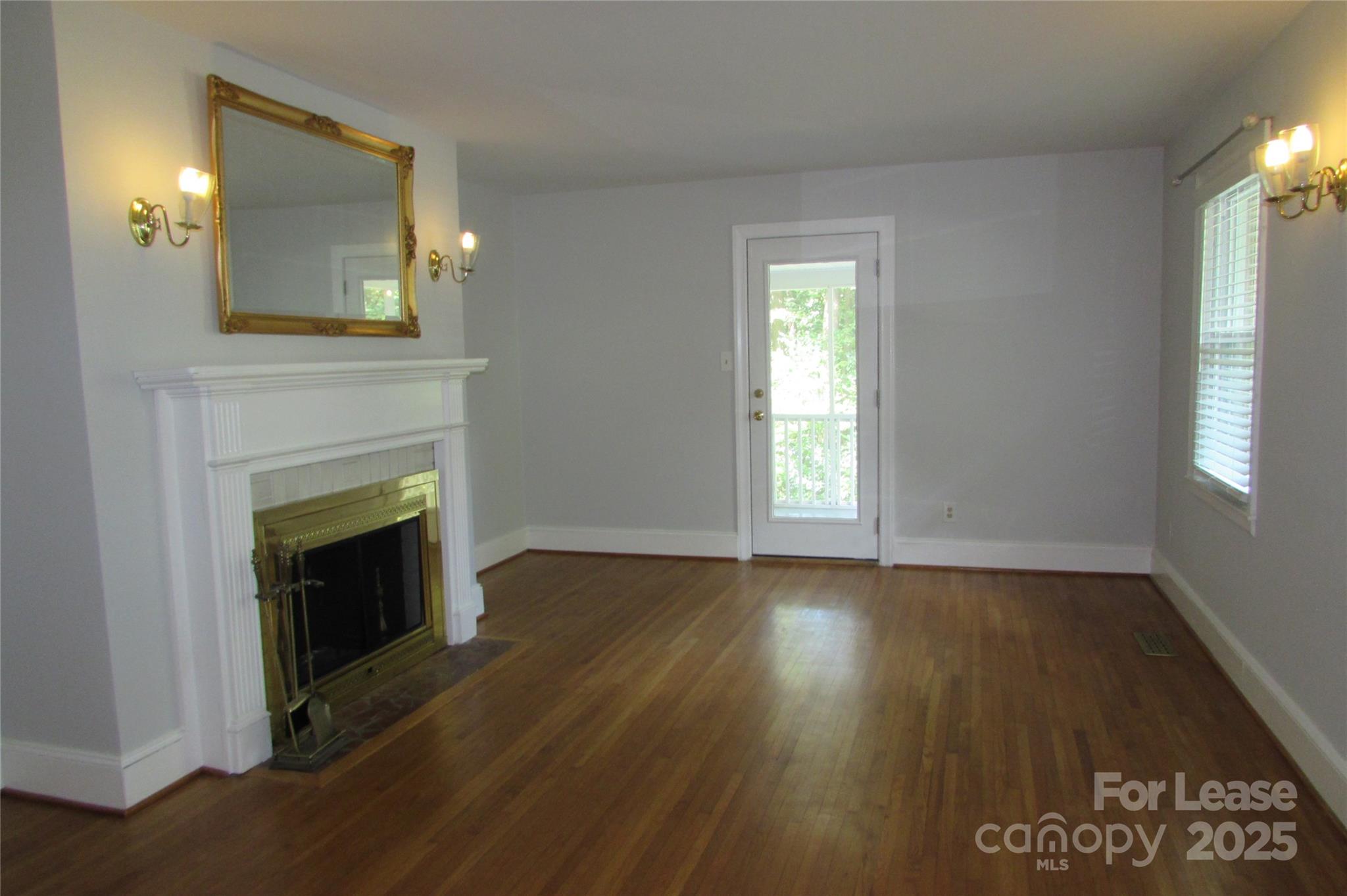 501 Dunham Road Gastonia, NC 28054 - Photo 4 of 28 an empty room with wooden floor a fireplace and windows