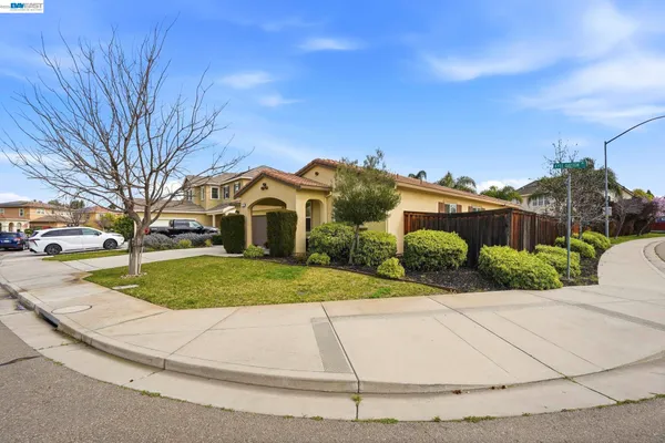 a view of a white house with a small yard and large trees