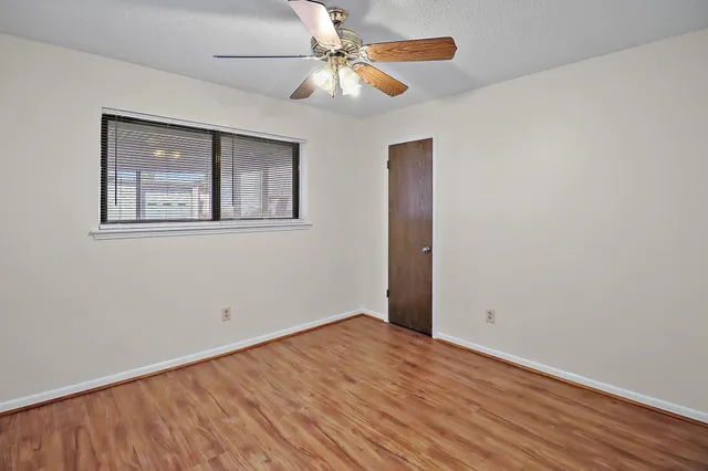 a view of an empty room with window and a chandelier fan