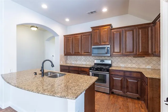 a kitchen with granite countertop a stove sink and cabinets