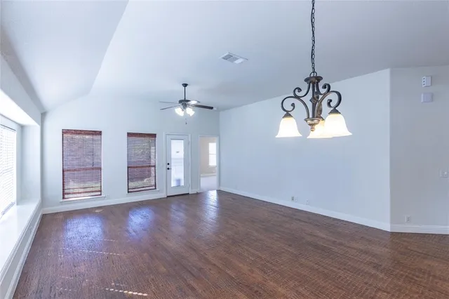 an empty room with wooden floor chandelier and window