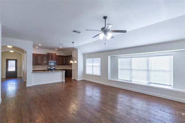 a view of an empty room with kitchen and window