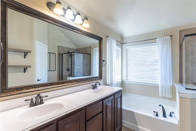 a bathroom with a bathtub a double vanity sink and mirror
