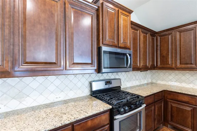 a kitchen with granite countertop wooden cabinets and a stove top oven