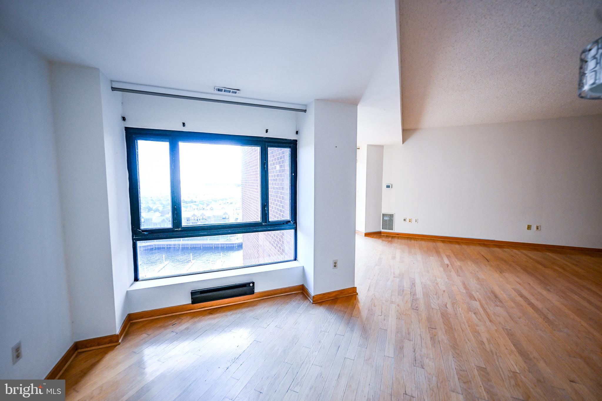 2515 Boston Street, Unit 1108 Baltimore, MD 21224 - Photo 11 of 40 an empty room with wooden floor and windows