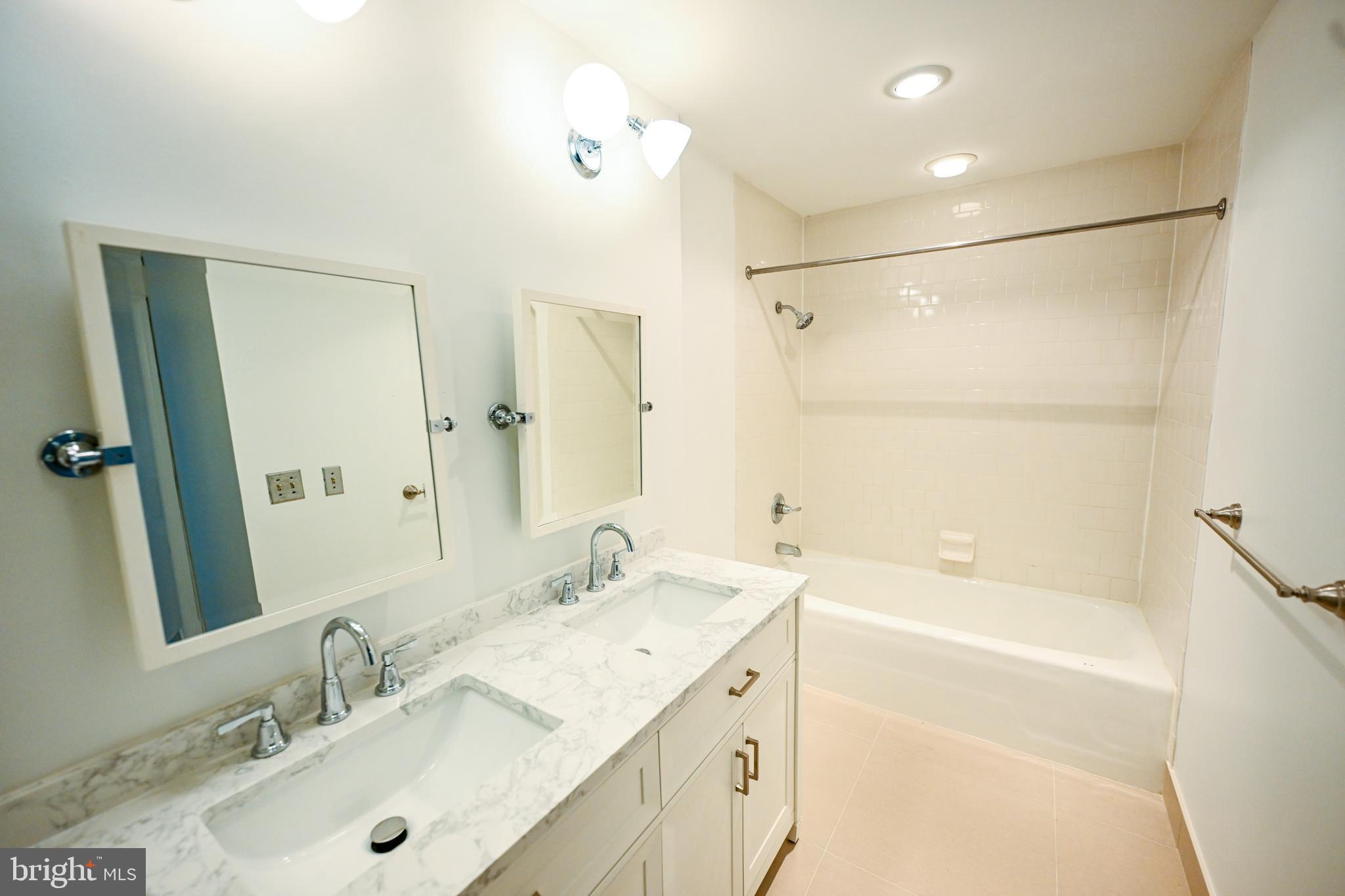 2515 Boston Street, Unit 1108 Baltimore, MD 21224 - Photo 24 of 40 a bathroom with a tub sink double vanity and a mirror