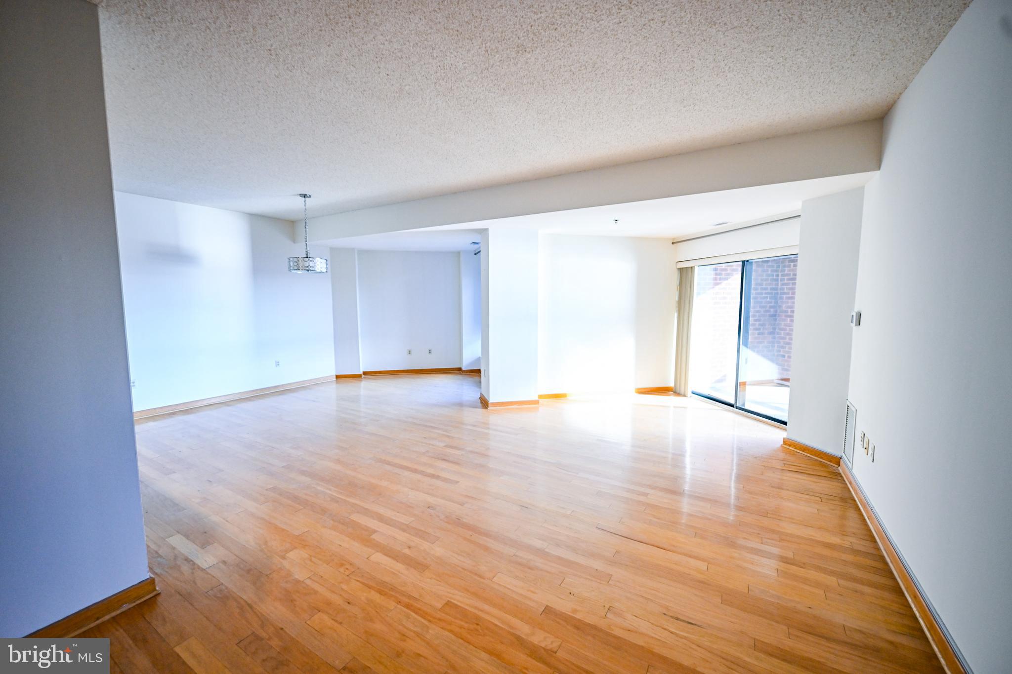 2515 Boston Street, Unit 1108 Baltimore, MD 21224 - Photo 5 of 40 a view of an empty room with wooden floor and a window