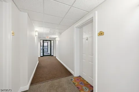 a view of a hallway with wooden floor and a bathroom