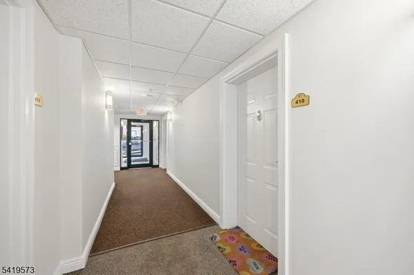 a view of a hallway with wooden floor and a bathroom