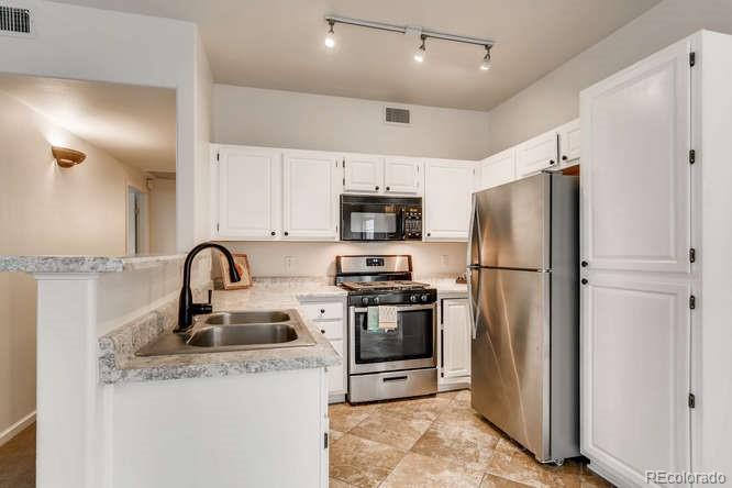 8312 Pebble Creek Way, Unit 104 Highlands Ranch, CO 80126 - Photo 2 of 12 a kitchen with stainless steel appliances granite countertop a refrigerator and a sink