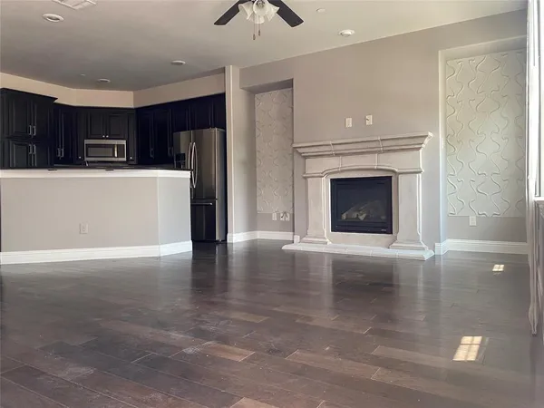 a view of an empty room with kitchen and a window