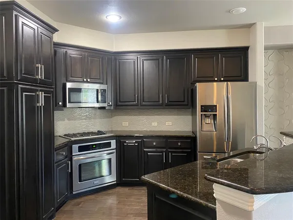 a kitchen with granite countertop a refrigerator stove and sink