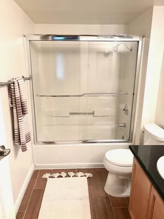 a bathroom with a granite countertop sink toilet a mirror and a shower