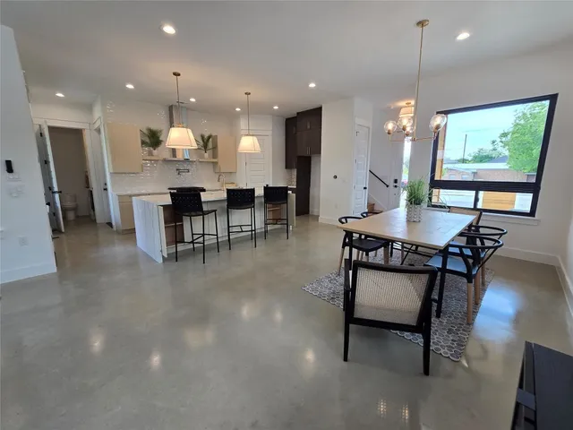 a dining hall with stainless steel appliances a dining table and chairs with kitchen view