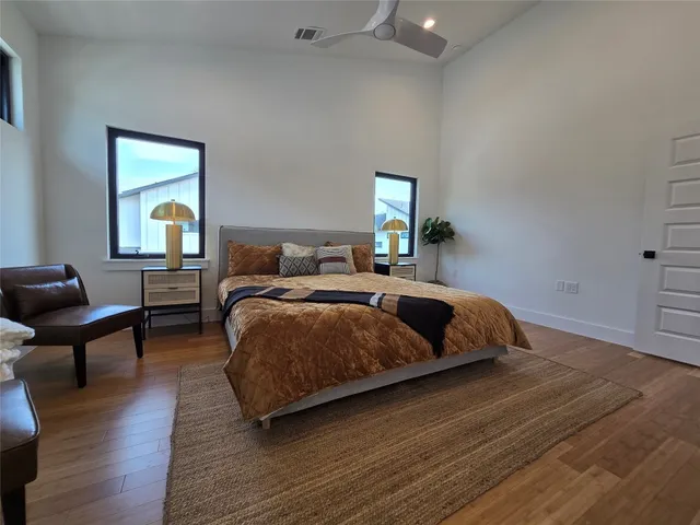 a bedroom with a bed lamps and wooden floor