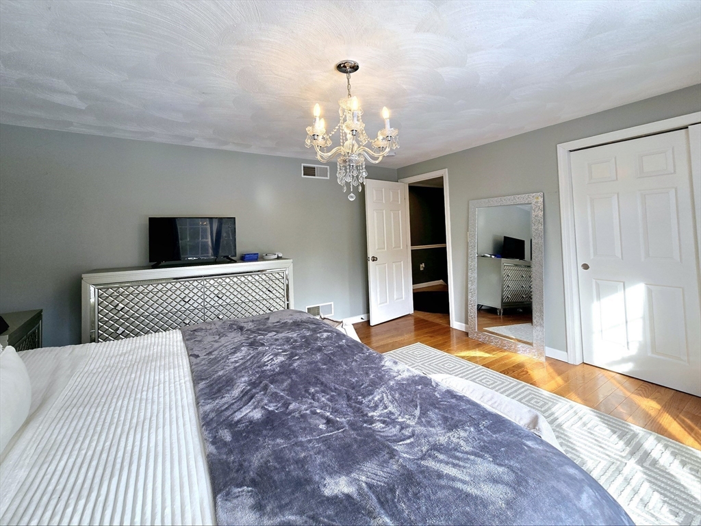 104 West Meadow Road Townsend, MA 01474 - Photo 30 of 42 a bedroom with a large bed and a chandelier