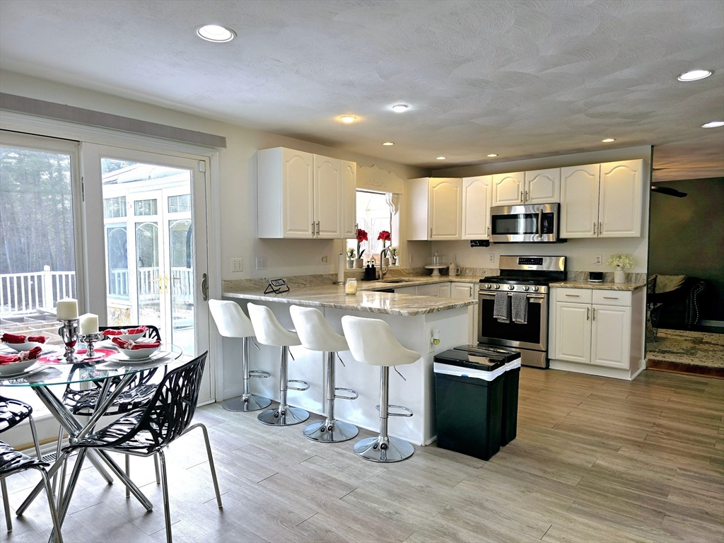 104 West Meadow Road Townsend, MA 01474 - Photo 5 of 42 a kitchen with stainless steel appliances granite countertop a stove top oven a sink dishwasher a dining table and chairs with wooden floor