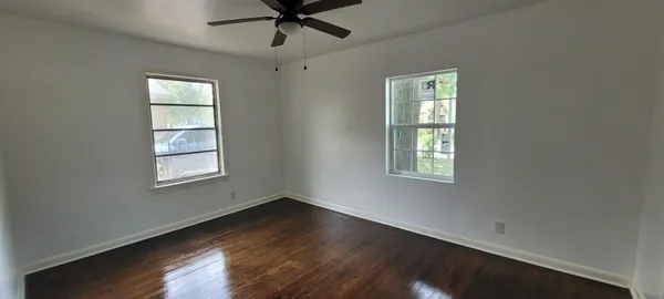 a view of an empty room with wooden floor and a window