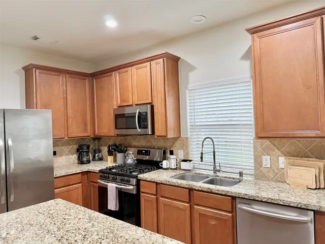 a kitchen with stainless steel appliances granite countertop a sink stove and refrigerator