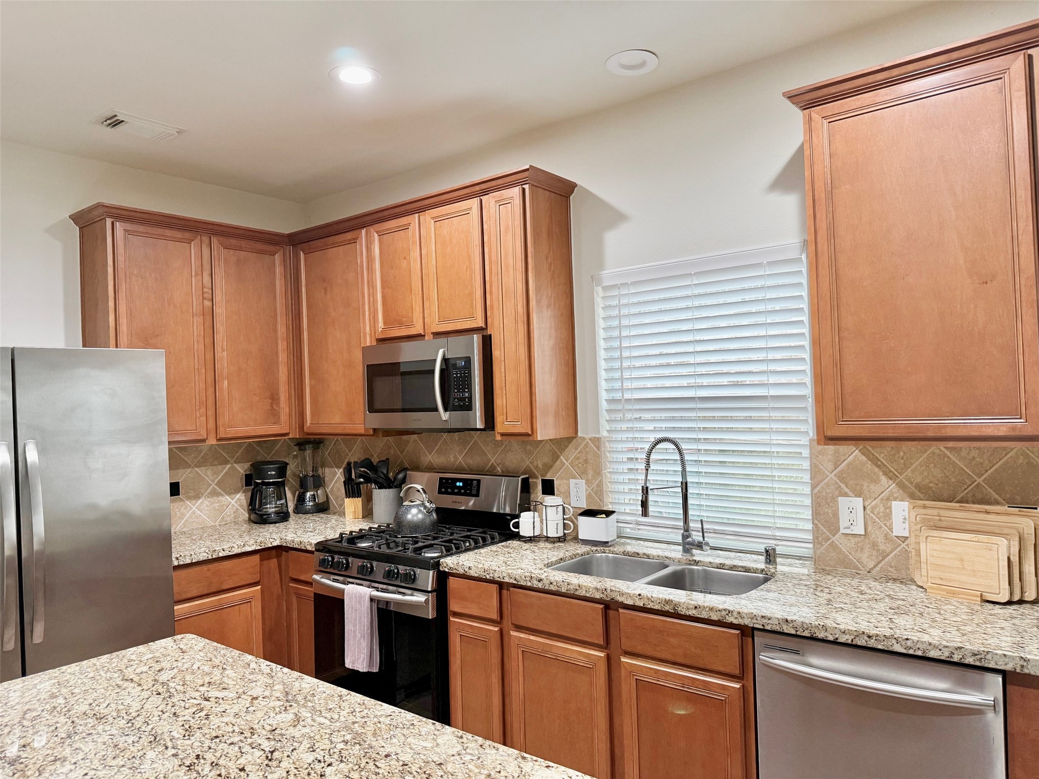 142 East Spindle Tree Circle The Woodlands, TX 77382 - Photo 24 of 37 a kitchen with stainless steel appliances granite countertop a sink stove and refrigerator