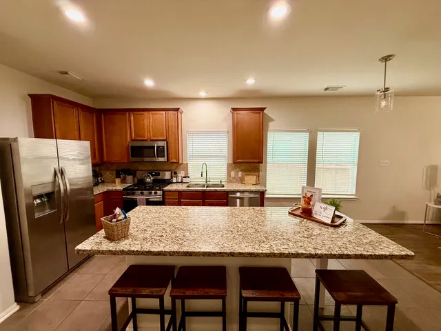 a kitchen with granite countertop sink refrigerator and microwave