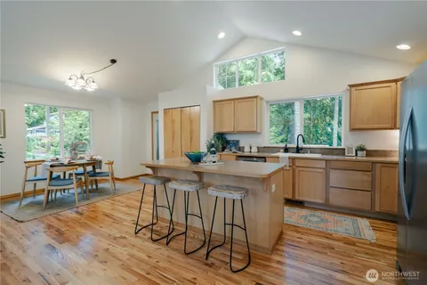 a kitchen with stainless steel appliances granite countertop wooden floor dining table and chairs