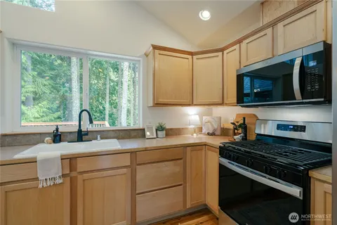 a kitchen with stainless steel appliances granite countertop a sink a stove a microwave and wooden cabinets