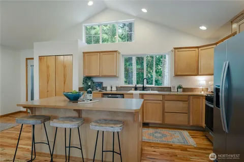 a kitchen with stainless steel appliances granite countertop a stove a sink a refrigerator white cabinets and wooden floor