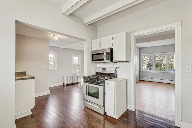 an empty room with wooden floor chandelier fan and windows
