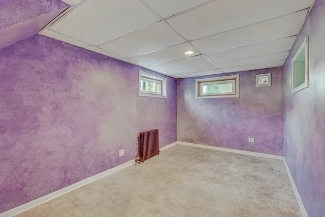 an empty room with wooden floor chandelier fan and windows