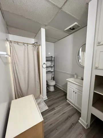 a bedroom with a bed wooden floor and flat screen tv